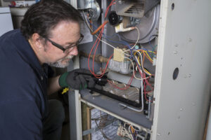 HVAC maintenance in Ocean County includes an inspection and cleaning as technician is shown doing in this picture